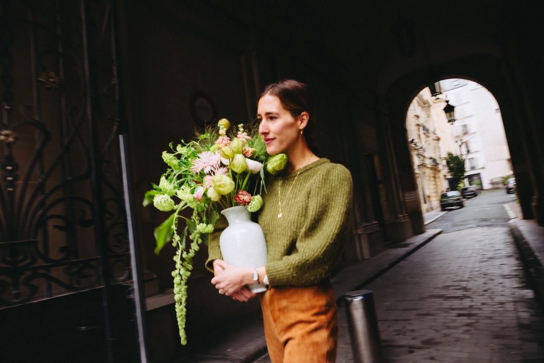 Fleuriste Bouquetier portant un bouquet de fleurs de saison dans un vase, dans un passage du 17e arrondissement de Paris