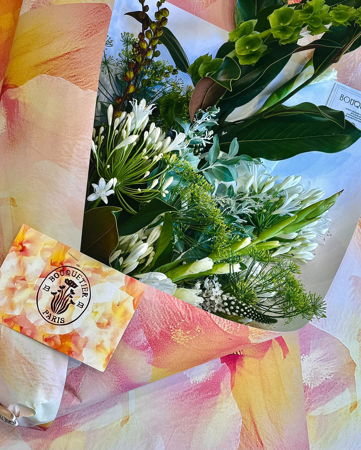 Le Végétal - bouquet blanc et vert d'agapanthes, feuillages variés, emballage aquarelle rose - Bouquetier Paris 17