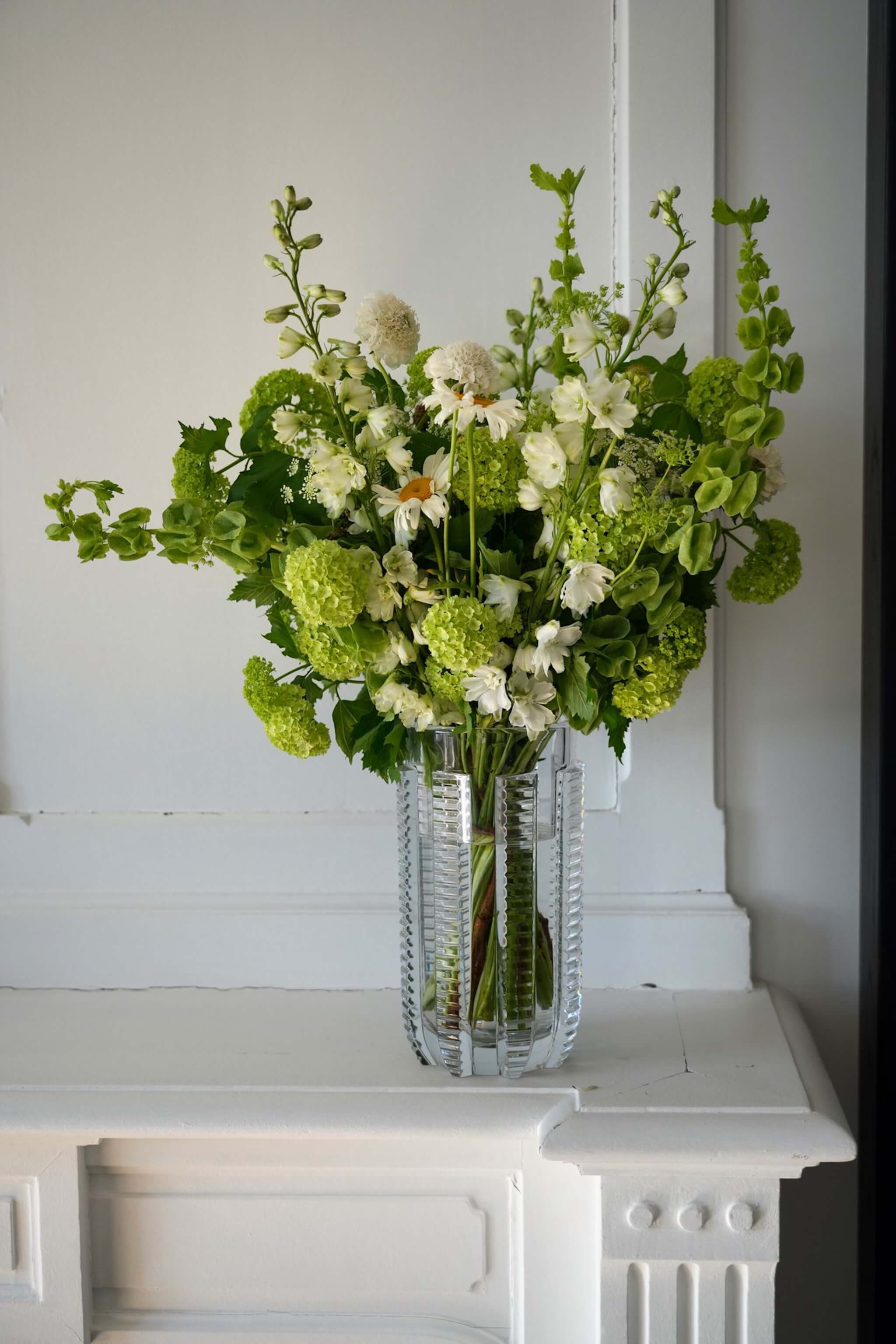 Composition de fleurs de saison blanches et vertes dans un vase en verre