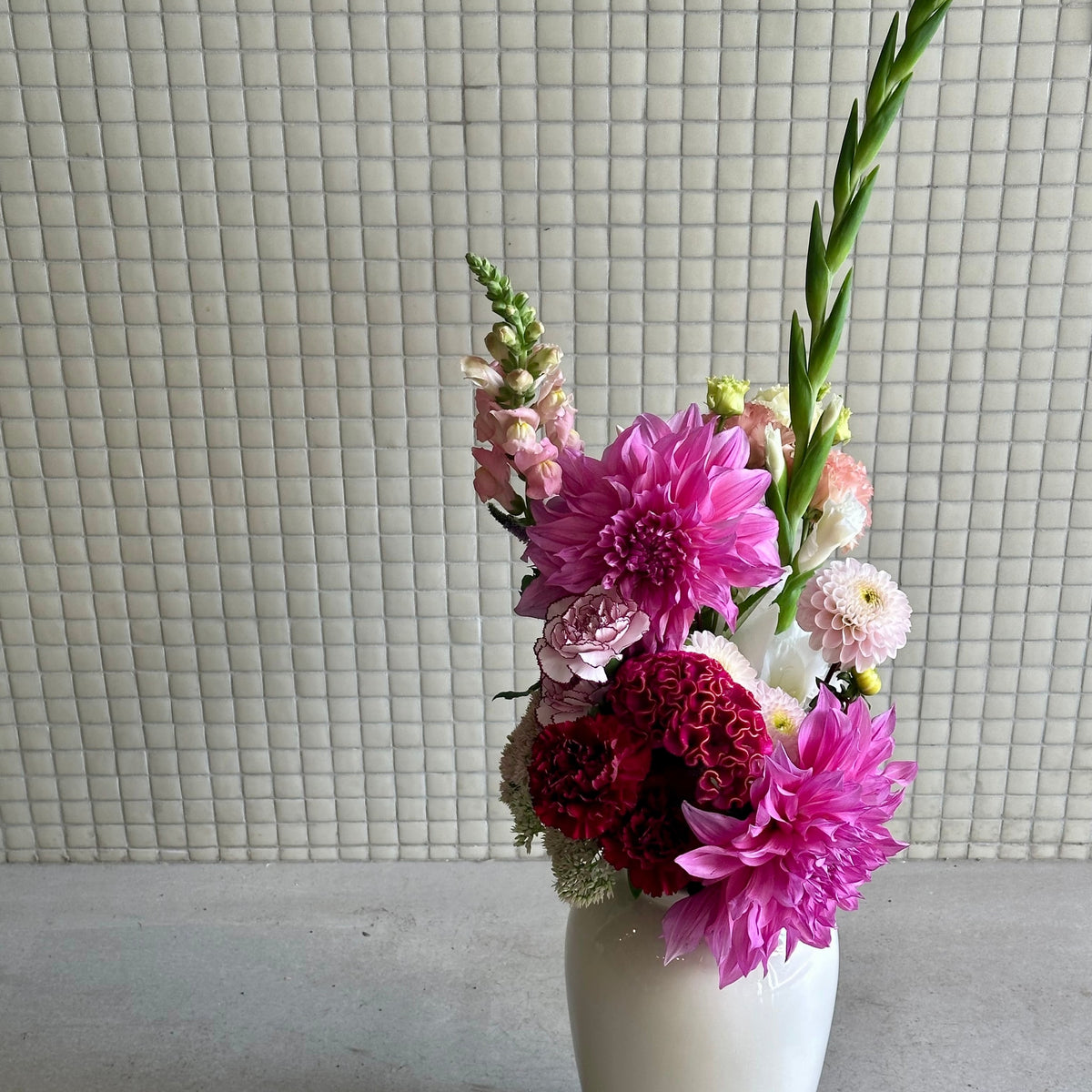 Le Passionné, dahlias fuchsia, célosie pourpre et glaïeul vert dans un vase blanc - Bouquetier Paris 17