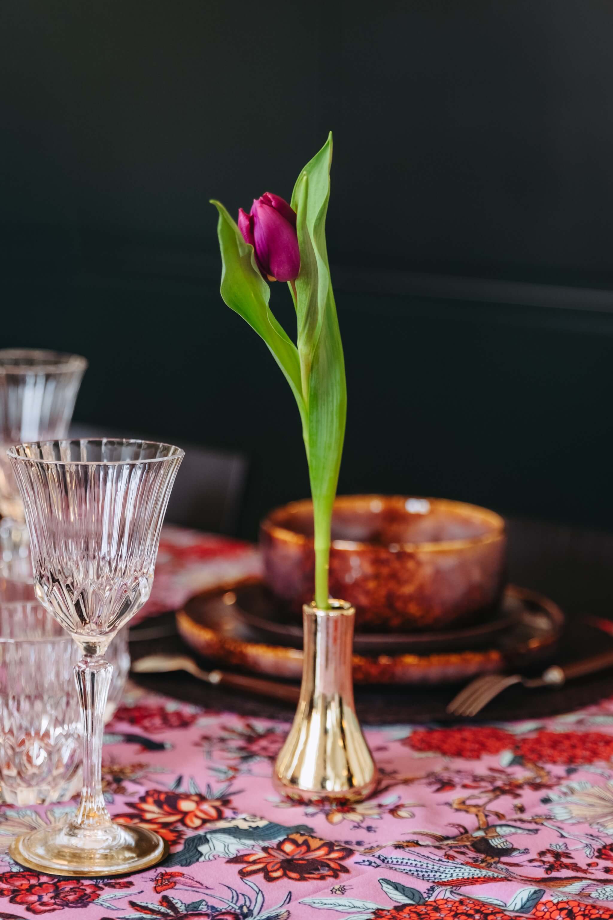 Fleur de saison présentée dans un petit vase sur une table de dîner