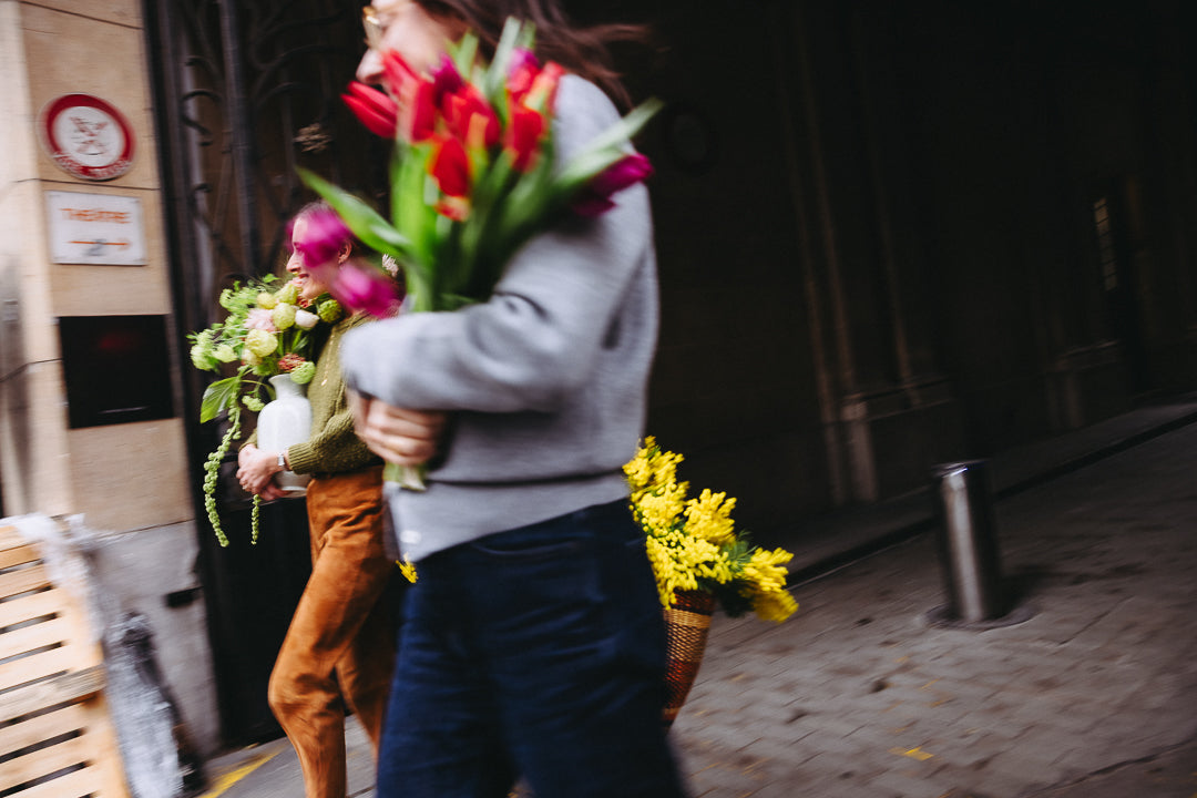 Personnes sortant avec des bouquets de fleurs de saison dans une rue parisienne