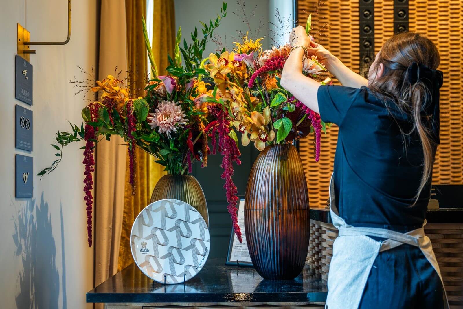 Fleuriste installant une composition de fleurs de saison dans le hall d’un hôtel
