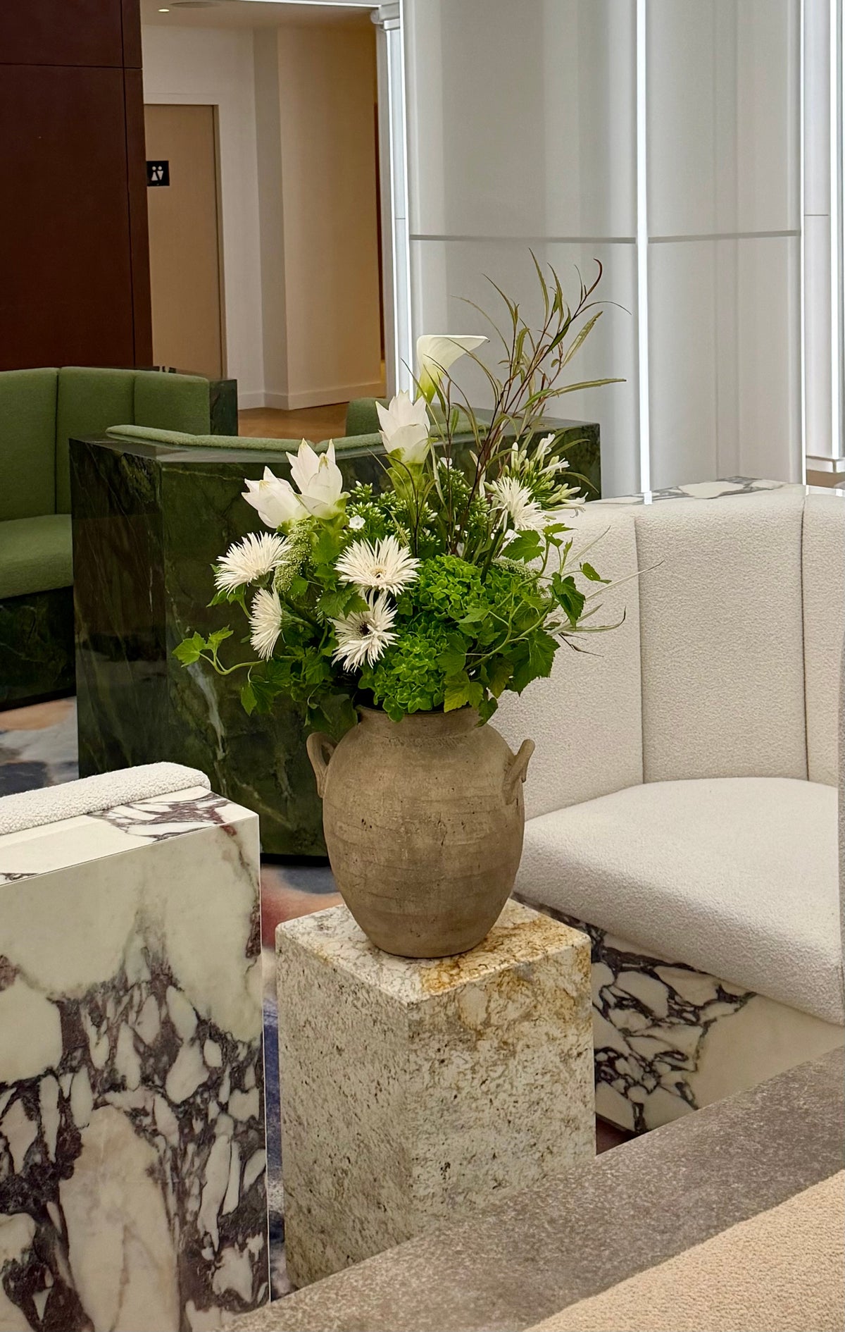 Composition florale blanche et verte dans une urne en gres, installee dans un espace lounge par Bouquetier Paris 17