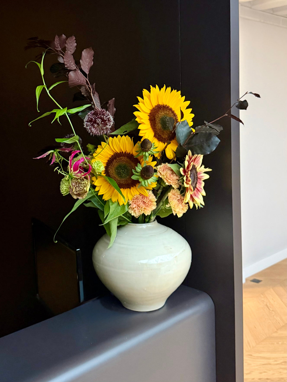 Bouquet de tournesols dans un vase bleu-gris, installation florale d'accueil par Bouquetier Paris 17