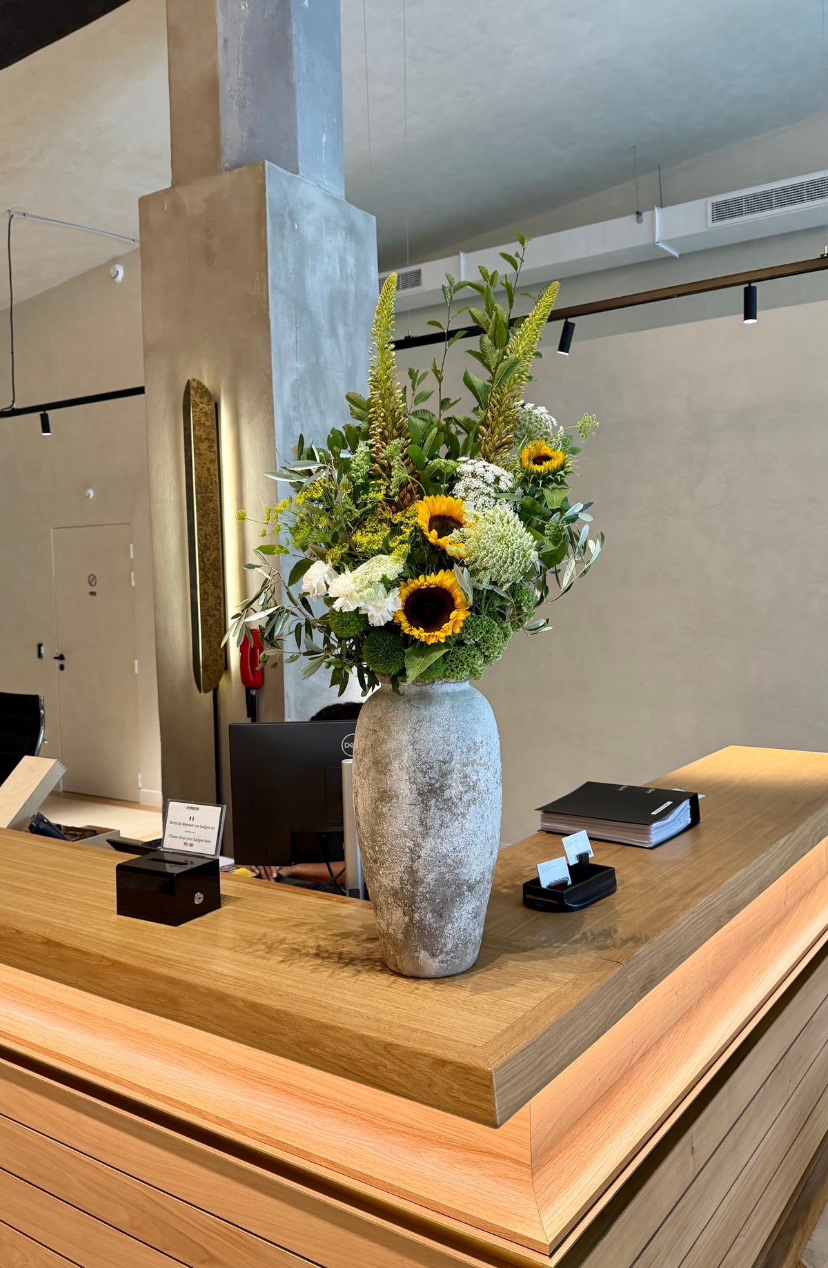 Bouquet de tournesols et fleurs blanches dans un vase en pierre, livre en accueil d'entreprise par Bouquetier Paris 17