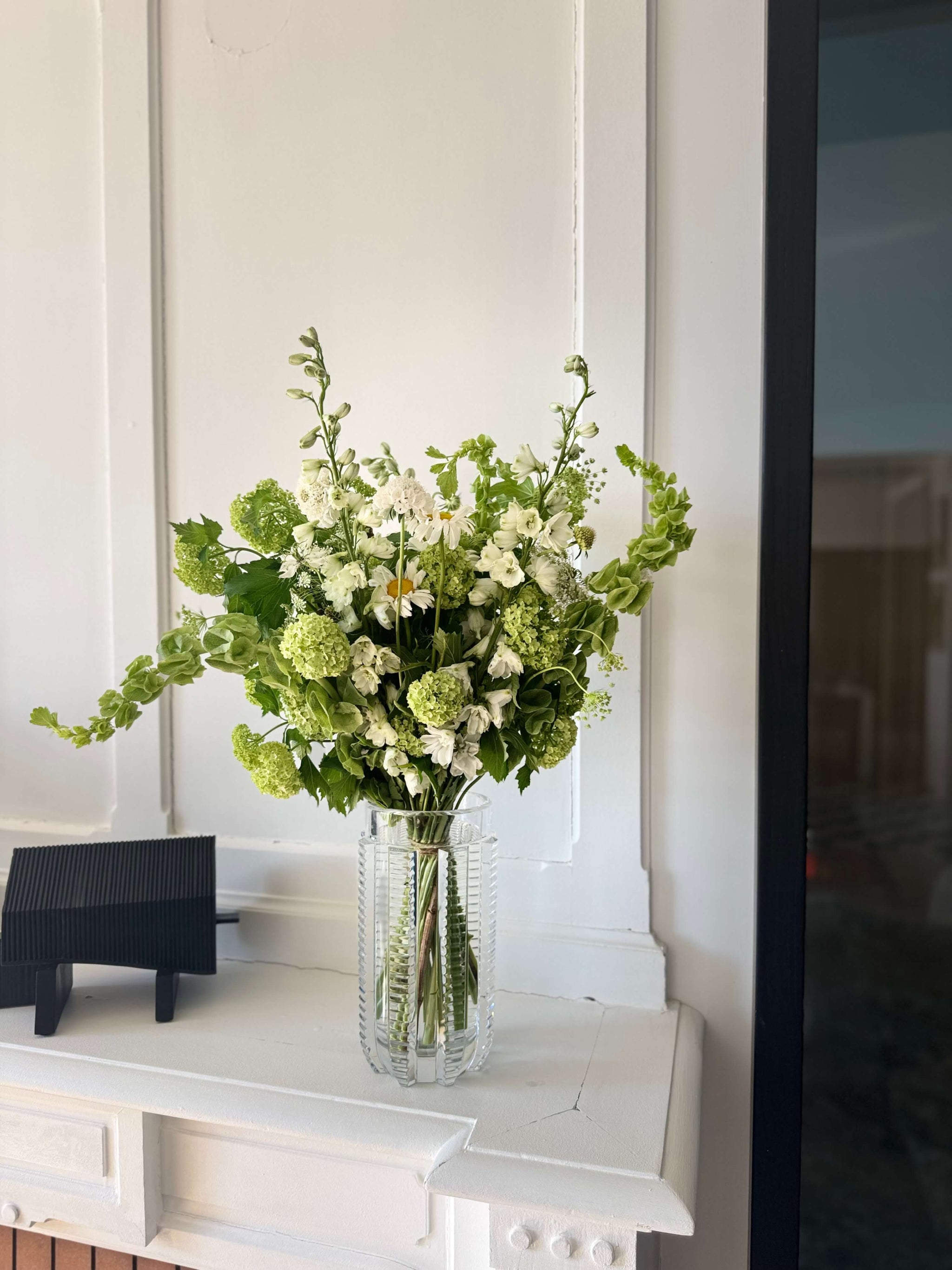 Composition de fleurs de saison vertes et blanches dans un vase en verre