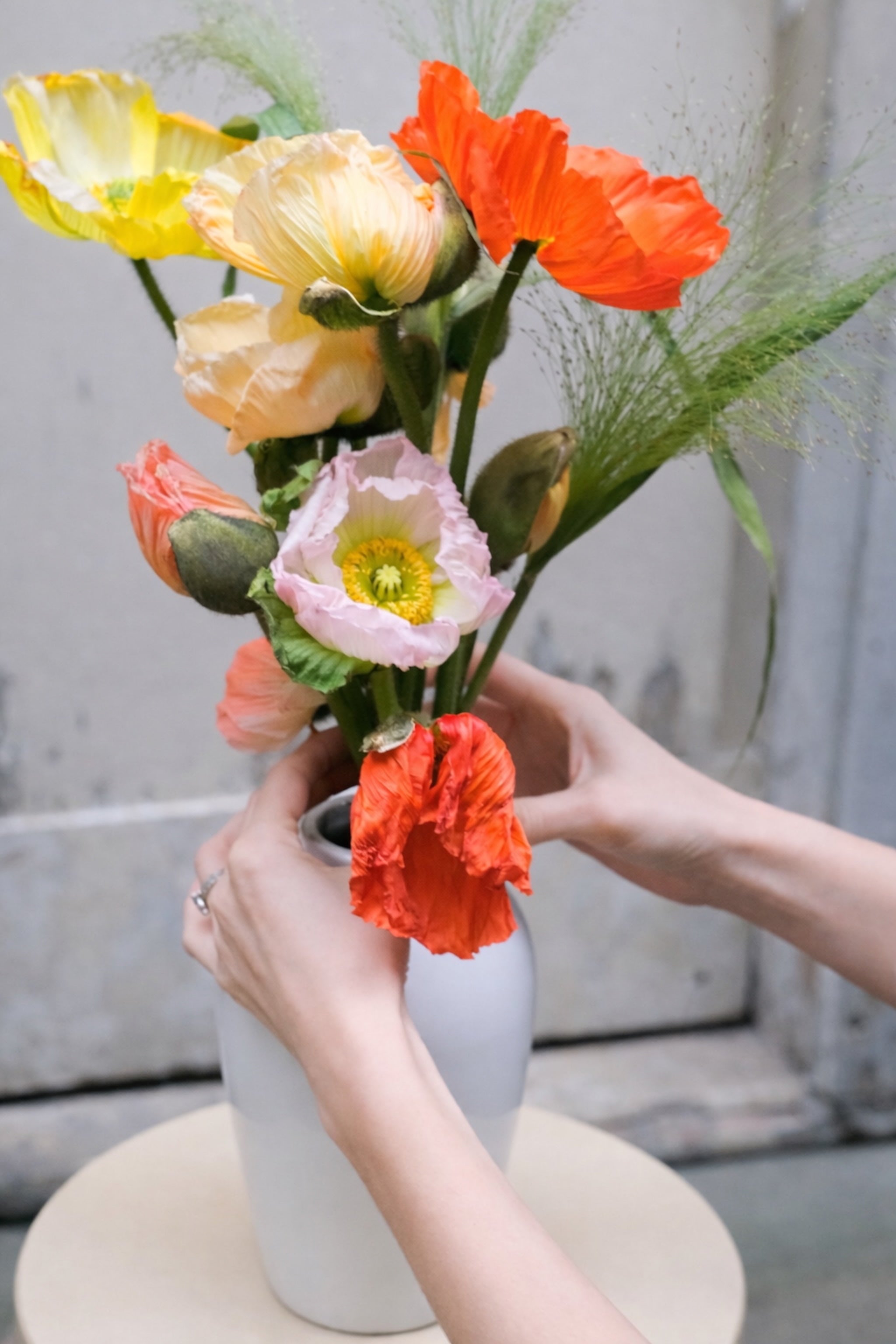 Geste du fleuriste lors de la composition de fleurs de saison en vase