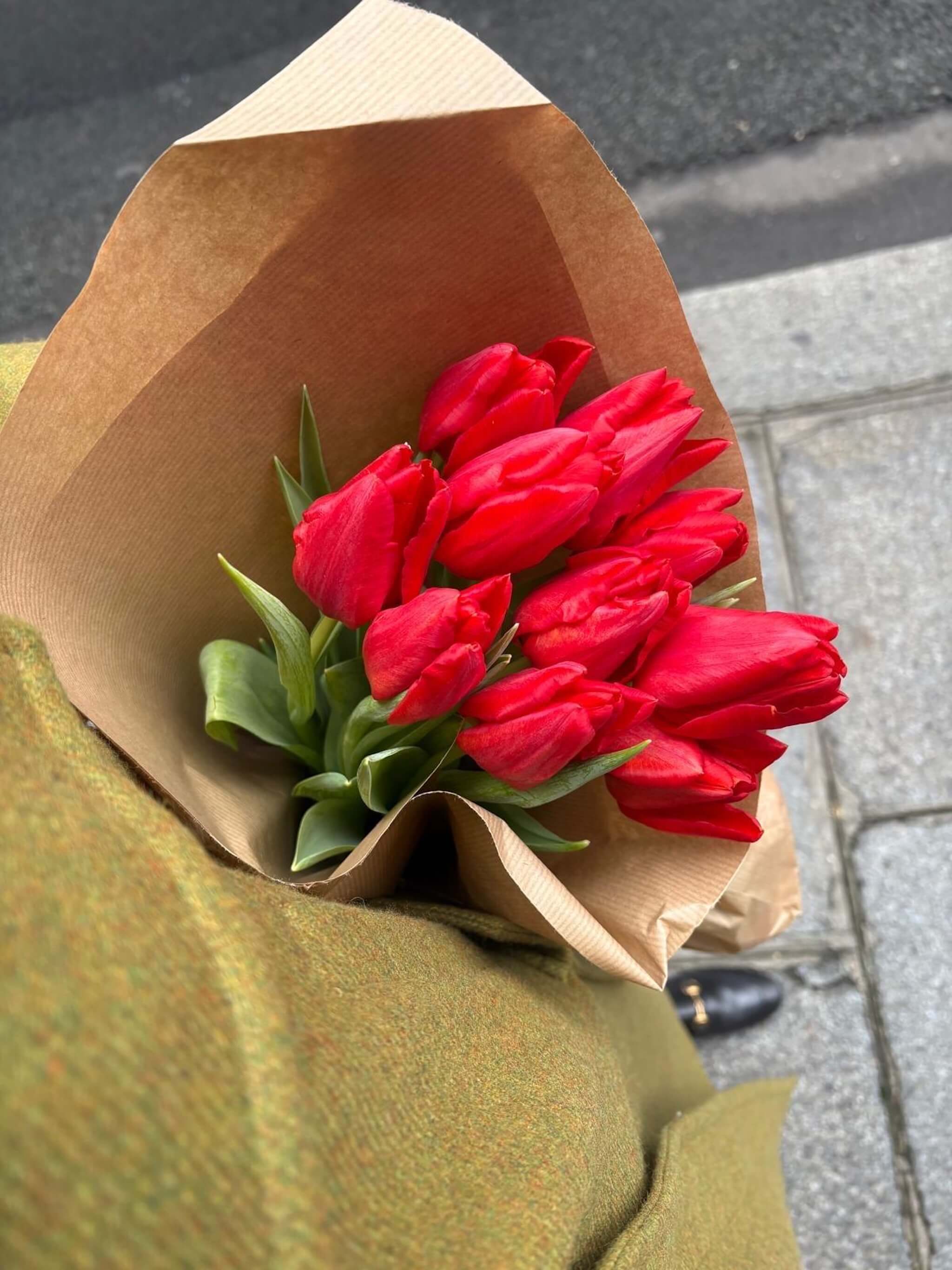 Botte de tulipes rouges achetée au marché, tenue à la main